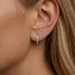 Close-up of an ear wearing a diamond hoop earring with a blurred background