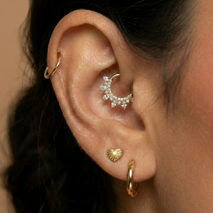 Close-up of ear with multiple gold and silver body jewelry piercings