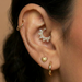 Close-up of ear with multiple gold and silver body jewelry piercings